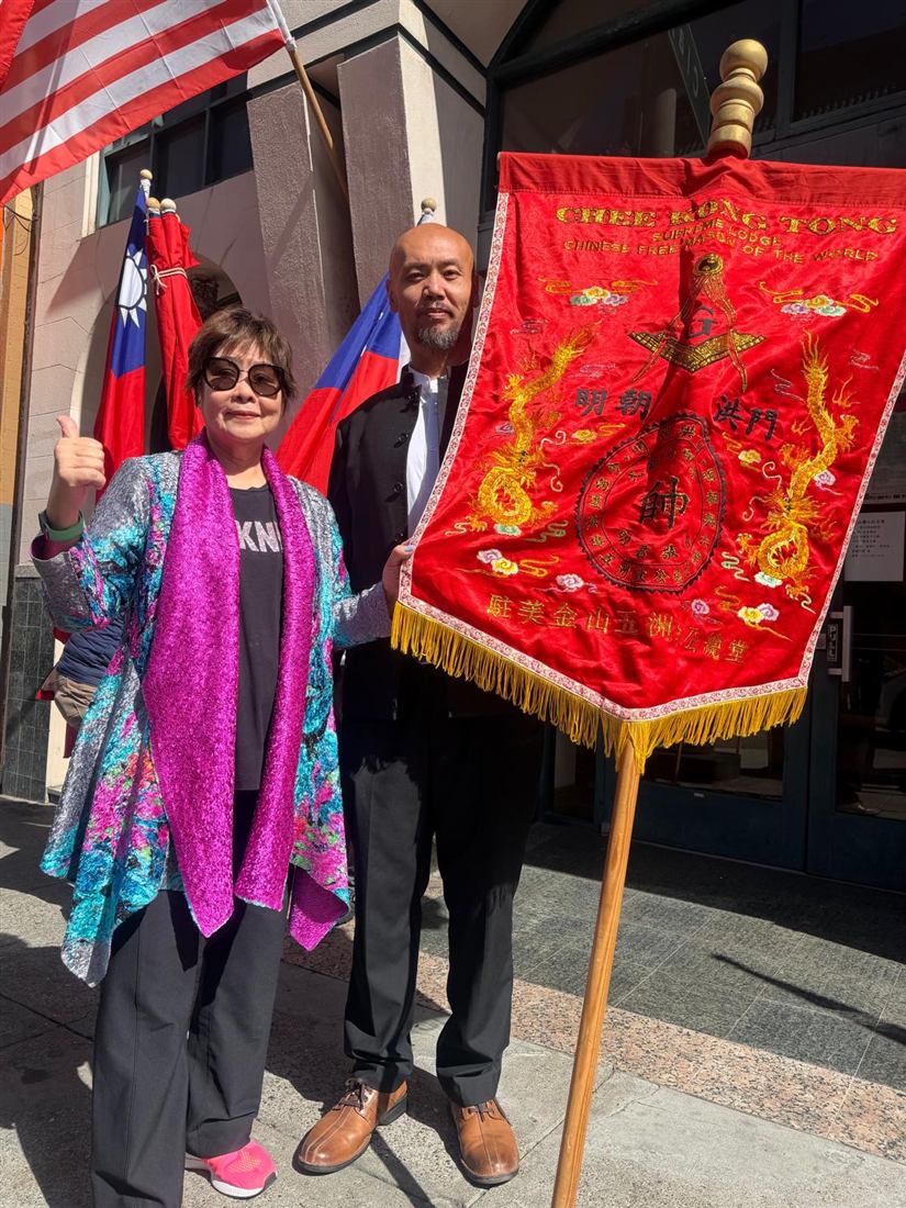 Two celebration participants beside the embroidered Supreme Lodge banner